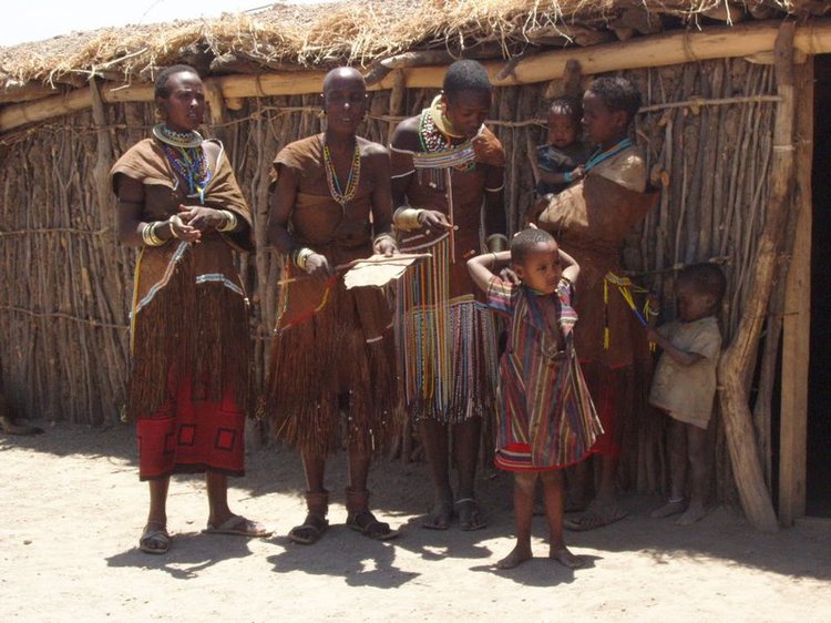 Massai women and childred standing in front of their hut