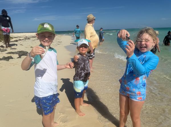 Bennett, Tav, Mia holding fish food for the stingrays at Honeymoon Harbor